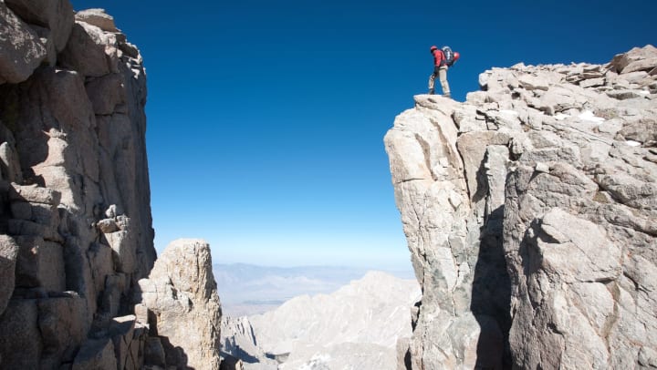 Backpacker standing at the edge of a cliff.