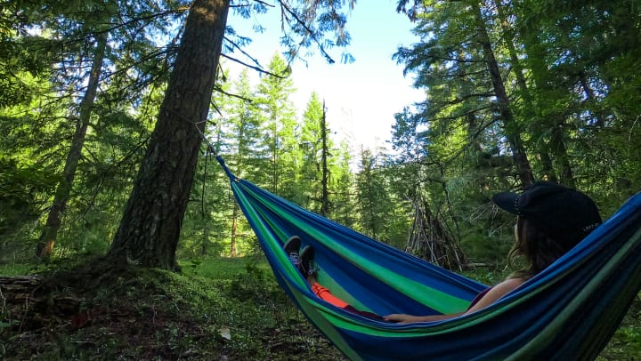 Woman on a hammock at sunset taking a picture with a digital table 