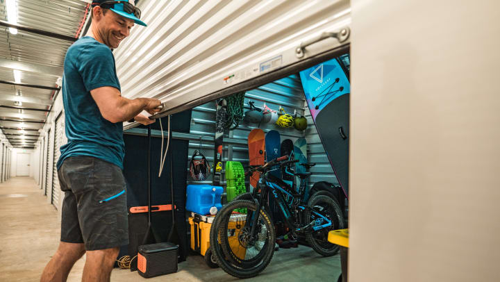 Man closing the door of a self storage unit full of outdoor gear